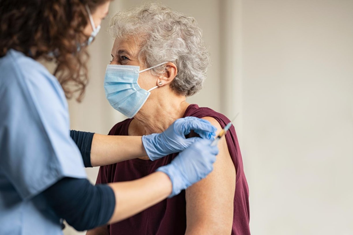 Dame met mondmasker krijgt vaccin